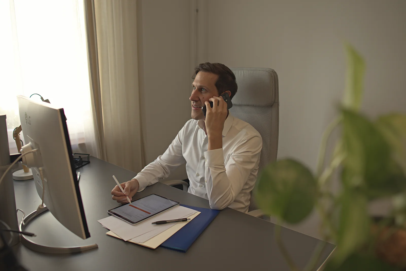 Telefonat am Schreibtisch mit Notizen und Tablet