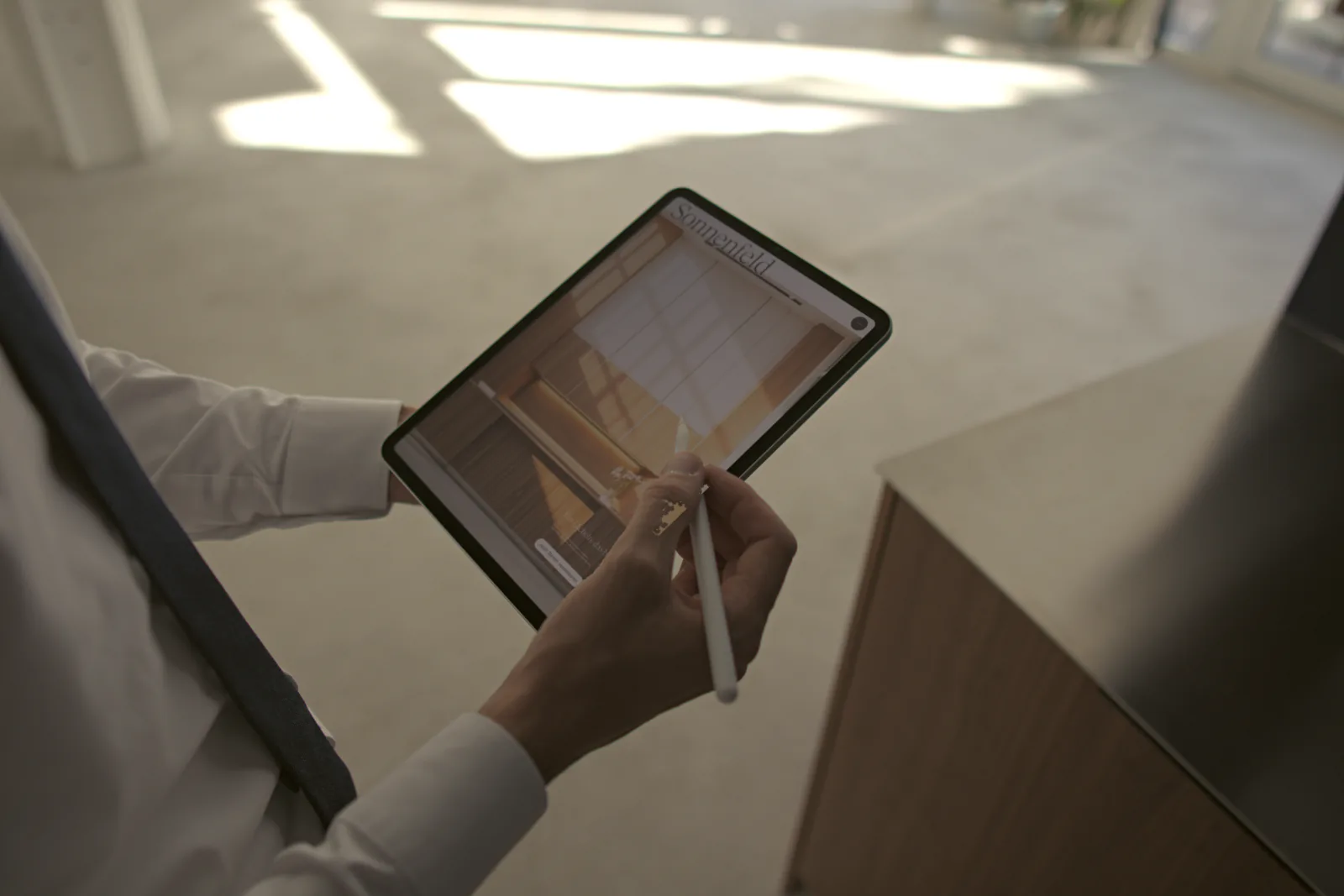 Hände mit Stift an einem Tablet, auf dem die Website der Praxis Sonnenfeld offen ist